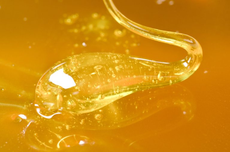 A close up of cannabis wax on a gold background.
