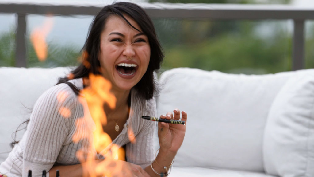 an individual sitting on a couch near an open fire. The person is vaping one of The Clears THC vape concentrates.