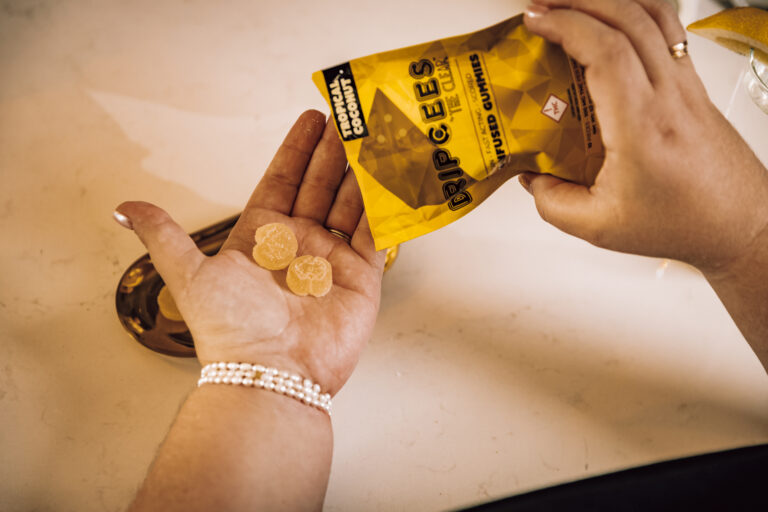 An individual putting two THC gummies into their palm from a package of cannabis infused gummies from The Clear. The flavor presented for the gummies is tropical coconut.